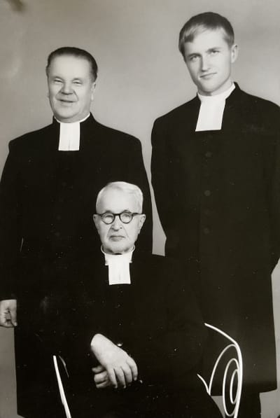 Kolme pappia virka-asussa muodollisessa ryhmäkuvassa, jossa kaikki katsovat kameraan.