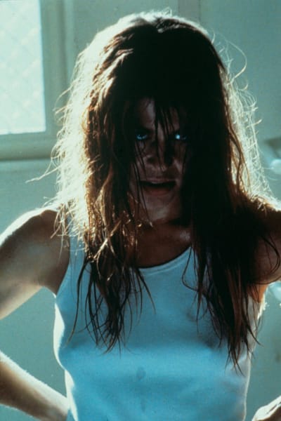 Närbild på Sarah Connor (Linda Hamilton) med rufsigt hår och vild blick.