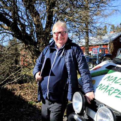 Raymond Wesander, med kalendern under armen, står lutad mot sin bil och njuter av majsolen