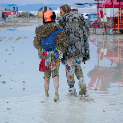 Två personer går igenom leran på Burning Man-festivalen.