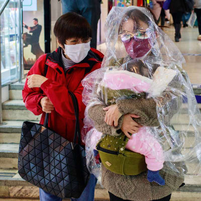 Nainen on suojannut itsensä ja lapsensa läpinäkyvällä sadeviitalla Hongkongissa.