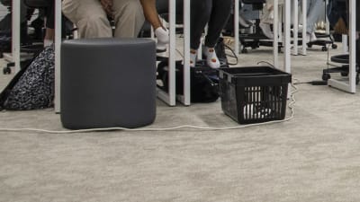 En skarvsladd ligger på golvet i ett klassrum där studerande sitter på stolar.