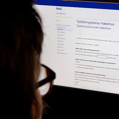 En person sitter framför en dator och ansöker om arbetslöshetsersättning via FPA.