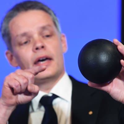 Nobelkommitténs Ulf Danielsson pekar på en svart boll han håller i handen medan han förklarar varför årets pris går till Roger Penrose, Reinhard Genzel, Andrea Ghez 