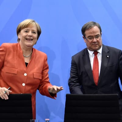 Angela Merkel och Armin Laschet på en presskonfes. Merkel ler medan Armin Laschet tittar ner i podiet.