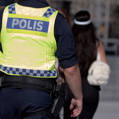 Kaksi poliisia huomioliivit päällään. Kuvassa mukana myös jalankulkijoita.