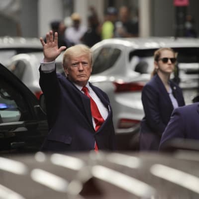 Donald Trump håller upp handen som om han skulle vinka.