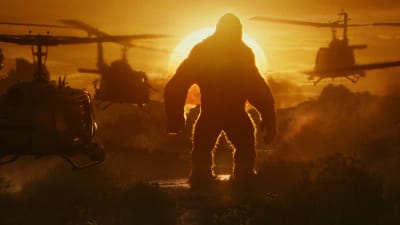 Kong står i solnedgången och ser hur en mängd stridshelikoptrar kommer flygande mot honom.