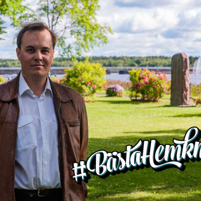 En man står i en park och tittar in i kameran.