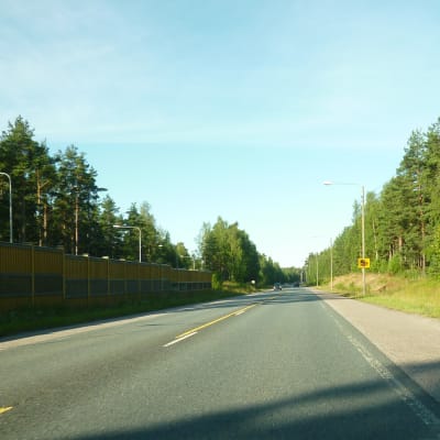 Riksväg 25 i Langansböle, ett bullerskydd i trä syns till vänster, en skylt om kameraövervakning till höger.