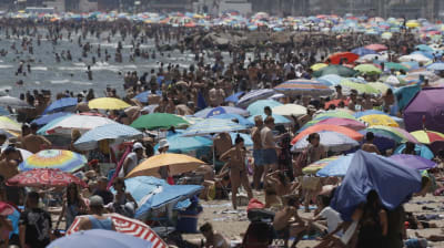 En strand full med människor och parasoll.