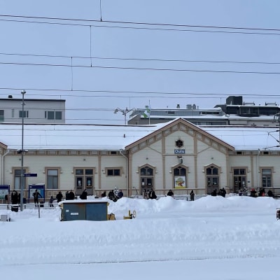 Oulun rautatieasema ja matkustajia laiturilla odottamassa junaa.
