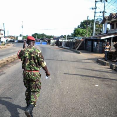 Sotilaspoliisi  tervehtii kadulla kulkevaa miestä Freetownissa Sierra Leonessa.