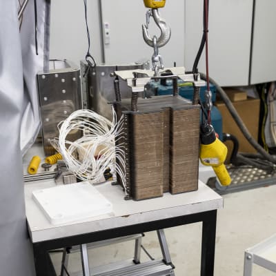 Laboratorion pöydällä ruskea elektrolyyseri, jonka kyljkeen on kytketty parikymmentä valkoista ohutta johtoa.