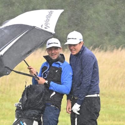 Sami Välimäki (oik.) ja caddie Väinö Viitaharju sateen suojassa Walesissa Euroopan kiertueella.