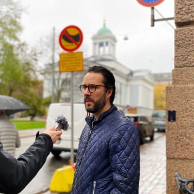 Marek Salermo blir intervjuad på Lönnrotsgatan, skylt med dubbdäcksförbud i bakgrunden.