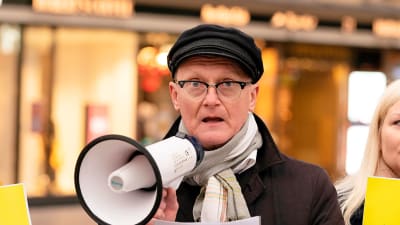 Amnesty Finlands verksamhetsledare Frank Johansson står och talar i en megafon.