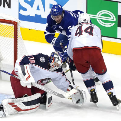 Joonas Korpisalo lägger vanten på pucken framför nästan på Auston Matthews.
