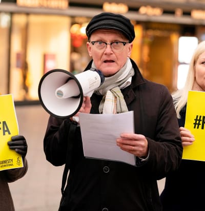 Amnesty Finlands verksamhetsledare Frank Johansson står och talar i en megafon.