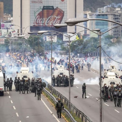 Polisen avfyrar tårgas mot tusentals demonstranter som blockerade en motorväg i Caracas.