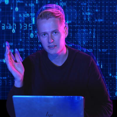 Redaktör Niklas Grönholm sitter framför en dator och berättar om AI-projekt i skolorna.