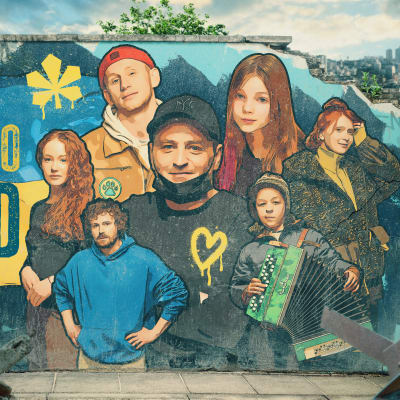 Sarjan kiovalaiset päähenkilöt ja teksti "He jotka jäivät" on maalattu betoniseen muuriin kaupungin raunioihin.