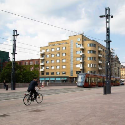 Polkupyöräilijä, ratikka ja jalankulkijoita Tampereen Hämeenkadulla.
