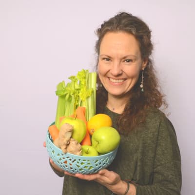 Tara Lange pitelee vihanneksia ja hedelmiä sisältävää astiaa käsissään.
