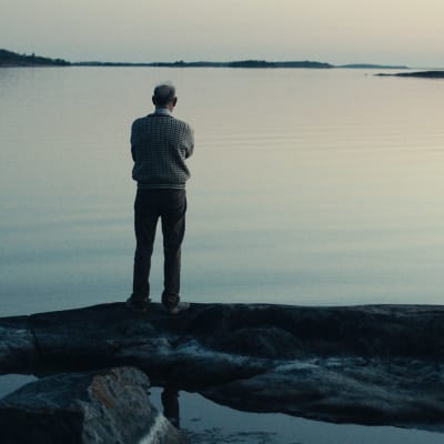 Anders Larsson tittar mot horisonten vid havsstranden. 