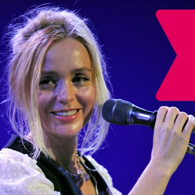 Lisa Ekdahl ler med öppen mun och håller med ena handen i en mikrofon som är i en mikrofonställning.