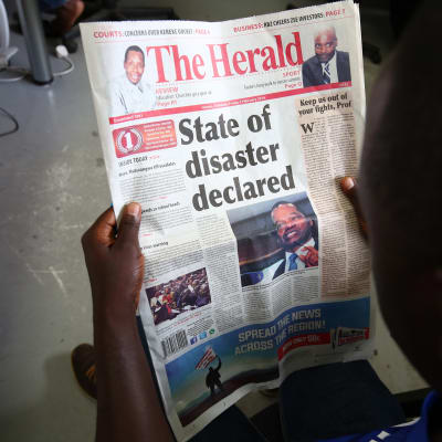 Mies lukee paikallislehdestä Zimbabwen presidentistä, joka julisti maataloustilanteen kansalliseksi katastrofiksi. 