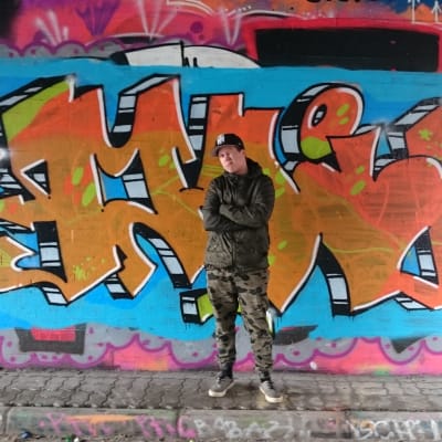 Mikko Könkkölä maalaamansa graffitin edessä.