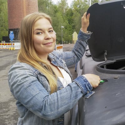 Nainen avaa jäteastian kantta.