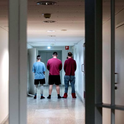 Kolme vankia selin vankilan käytävällä