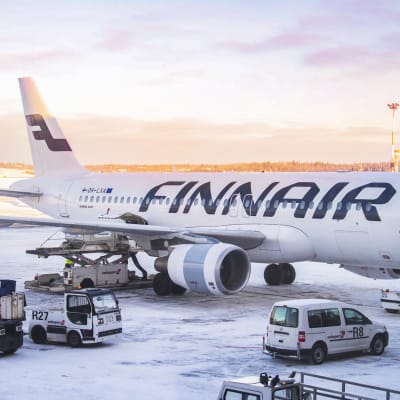 Ett Finnairflyg på marken vid Helsingfors-Vanda flygplats. På marken finns snö. I bakgrunden syns rodnad himmel.
