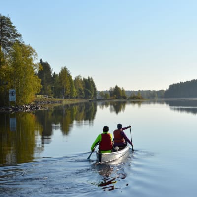 Kaksi ihmistä meloo kanootilla Kajaaninjoella.