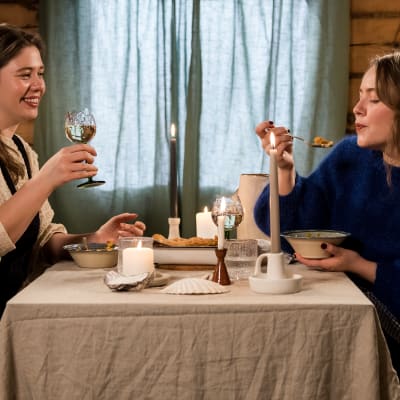 Tara och Malin sitter och äter vid ett bord i andra säsongen av Kan vi bara få njuta