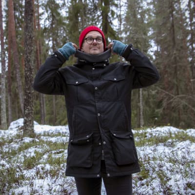 Wille Lehtovaara nostaa takin kaulusta metsässä