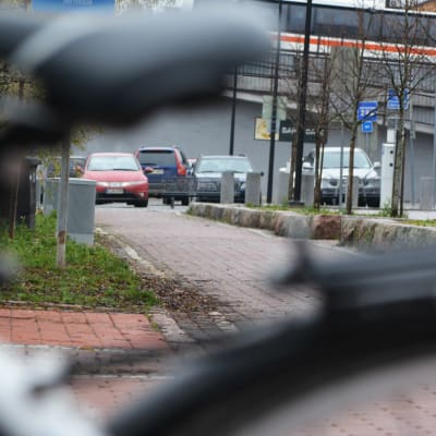 En cykelväg som slutar i en parkeringsplats. I förgrunden en cykel.