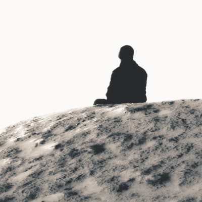 Person sitter ensam på en klippa.