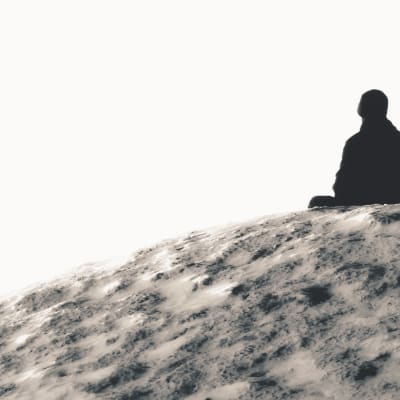 Person sitter ensam på en klippa.