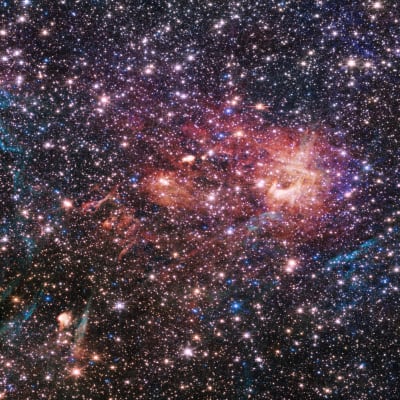 En galax skimrar i turkosy/cyan till vänster och rosa till höger. Överallt syns ljuspunkter och stjärnor av olika lyskraft.