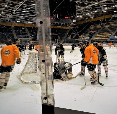 Oulun Kärppien jääkiekkopelaajat harjoittelevat Raksilan jäähallissa. Kuvattu suojaplexin läpi.