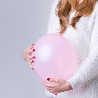 Kvinnan håller en luftballong vid sin mage