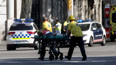 Räddningsmanskap bär på en bår med en skadad man efter att en bil körde in i folkmassa i Barcelona.
