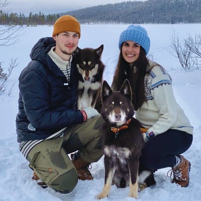 Petteri Morottaja ja Roosa Kukkola poseeraavat porokoiriensa kanssa Inarin Riutulassa Muddusjärven lumisissa maisemissa.