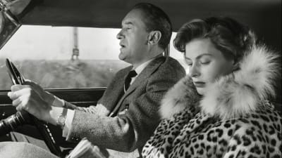Mies (George Sanders) ajaa autoa, matkustajan paikalla istuu nainen (Ingrid Bergman) leoparditurkissa ja selaa matkaopasta. Kuva elokuvasta Matka Italiaan (Matka Italiassa, Viaggio in Italia).