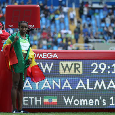 Almaz Ayana bredvid en skylt med världsrekordtiden.