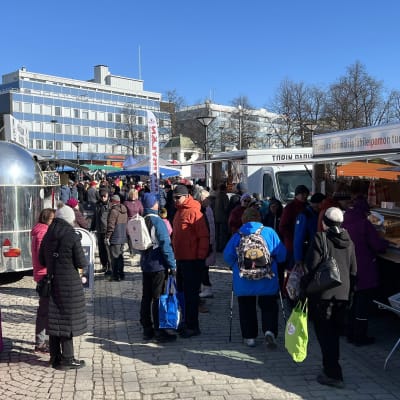 Ihmisiä ja torikauppiaita huhtikuun alun aurinkoisena päivänä Hämeenlinnan torilla.