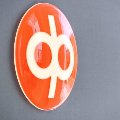 Op:s orange logga på en grå vägg.